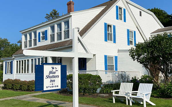 An exterior view of a building with white siding and blue shutters.
