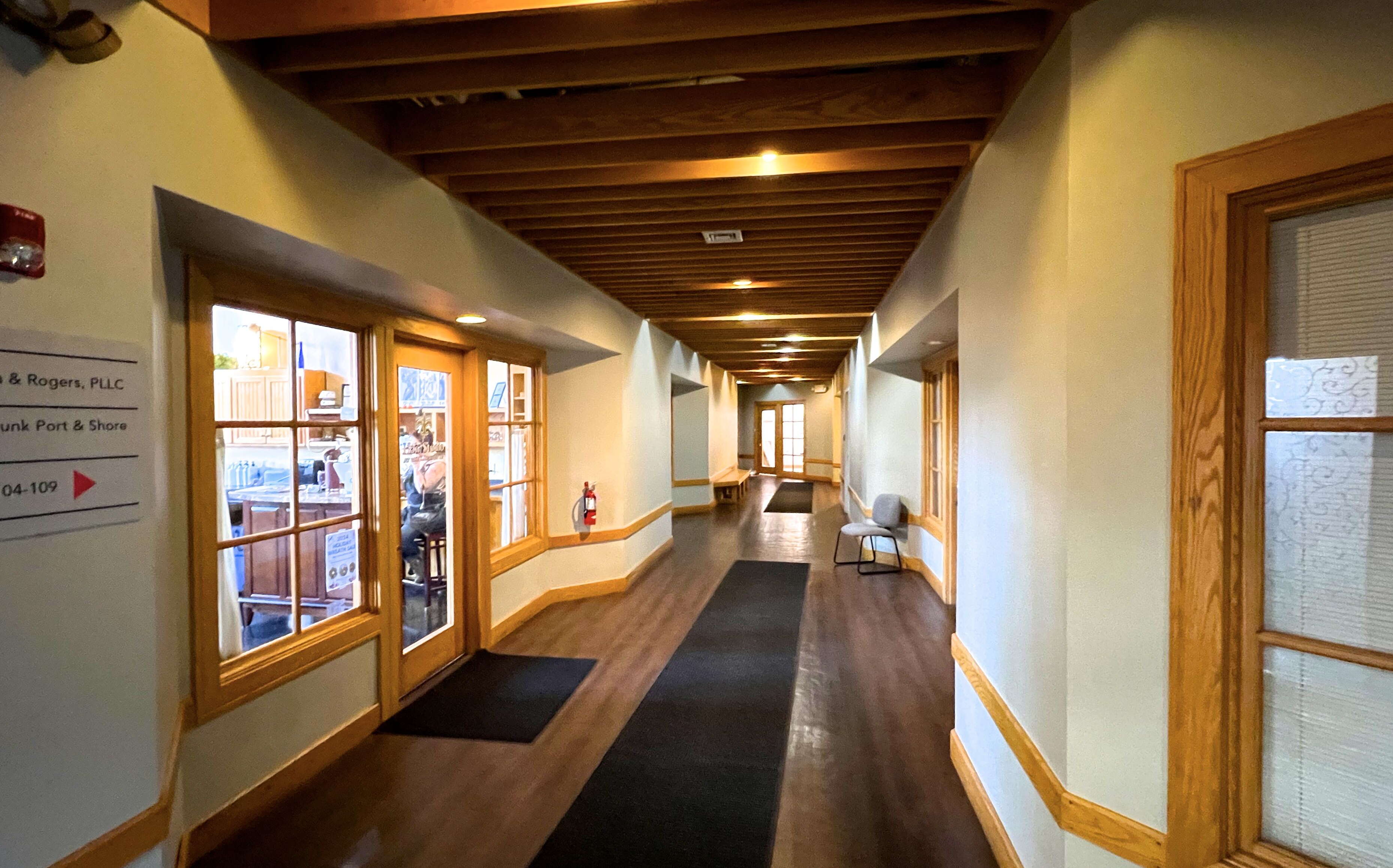 A hallway has white walls with wood trim and a wood floor.
