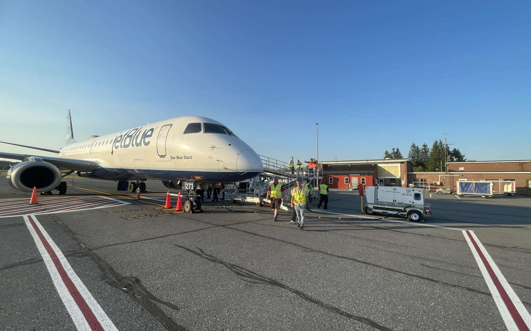A plane sites on an apron with buildings in the background.