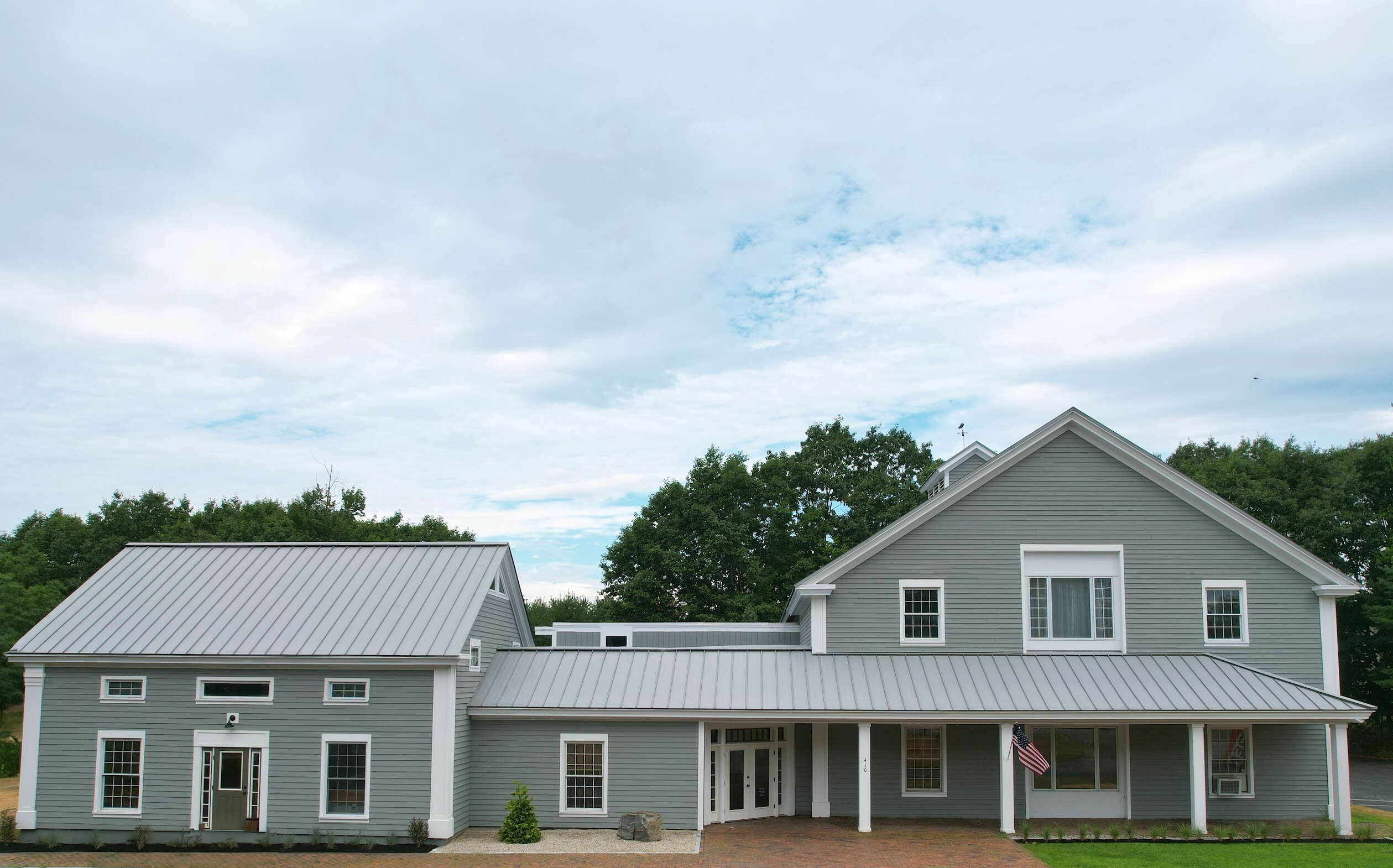 An exterior view of a building with gray siding and white trim.