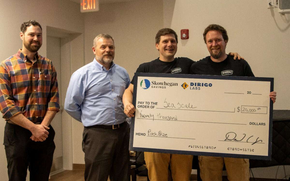 Four people pose with an oversize check.