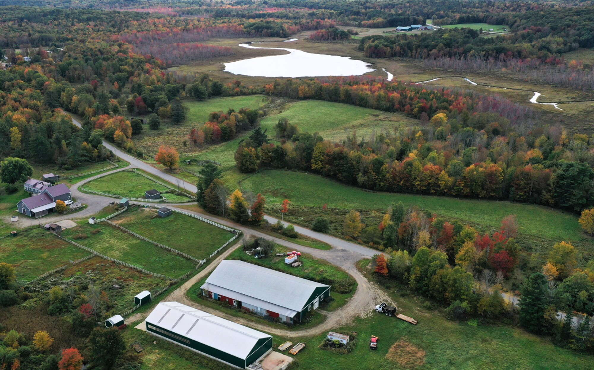 An aerial view of fields, buildings and woods.