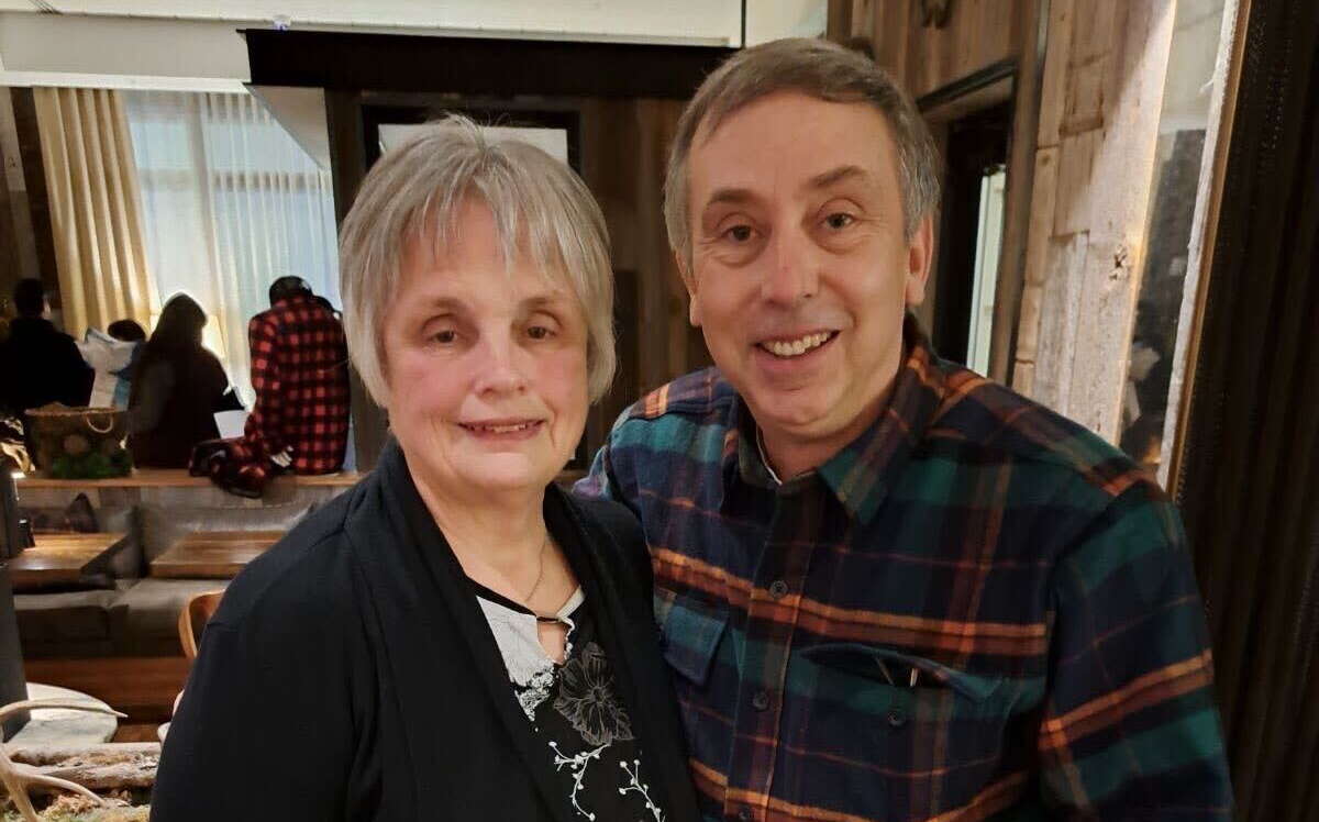 Two people pose in a room.