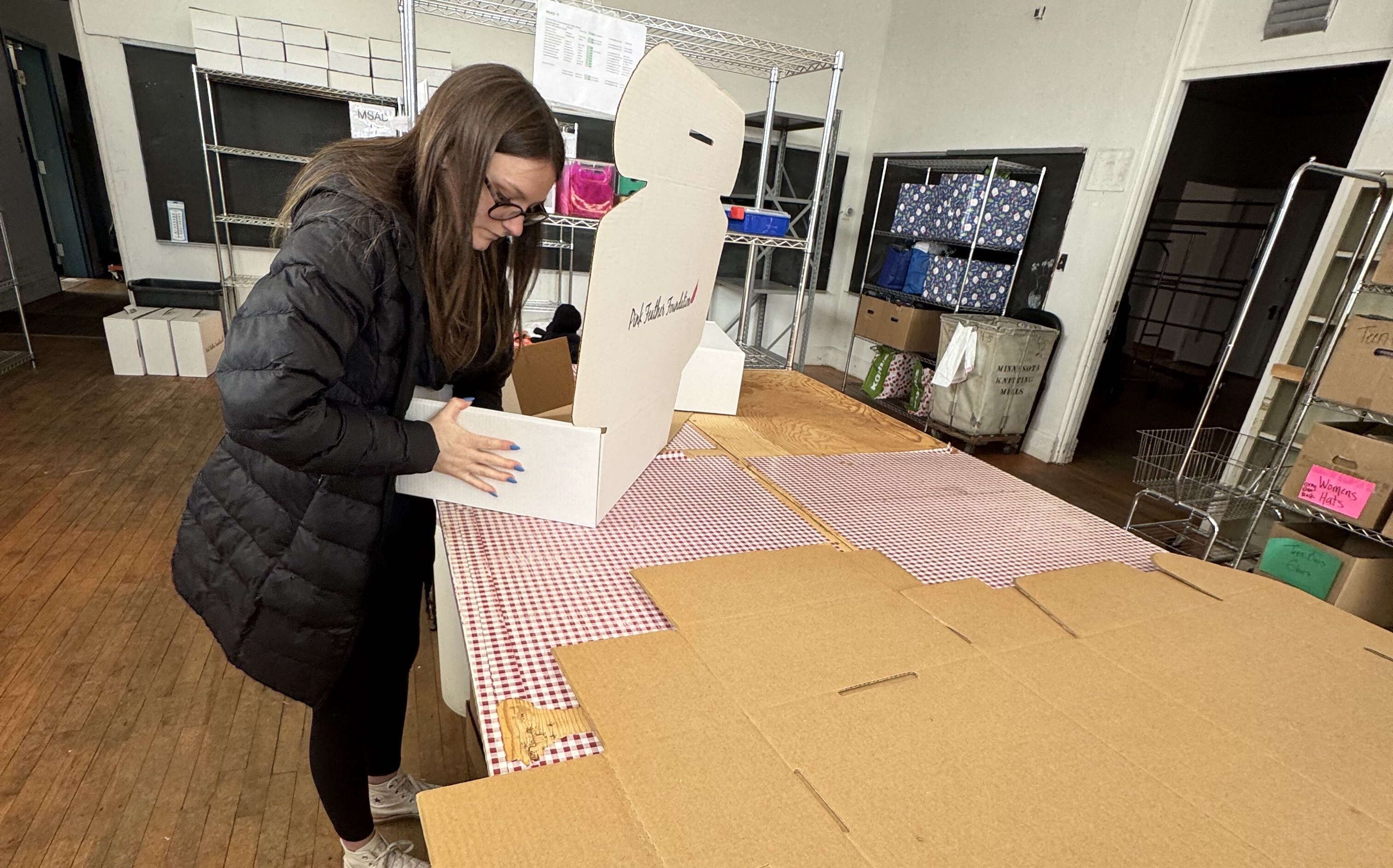 A person stands at a table with cardboard.