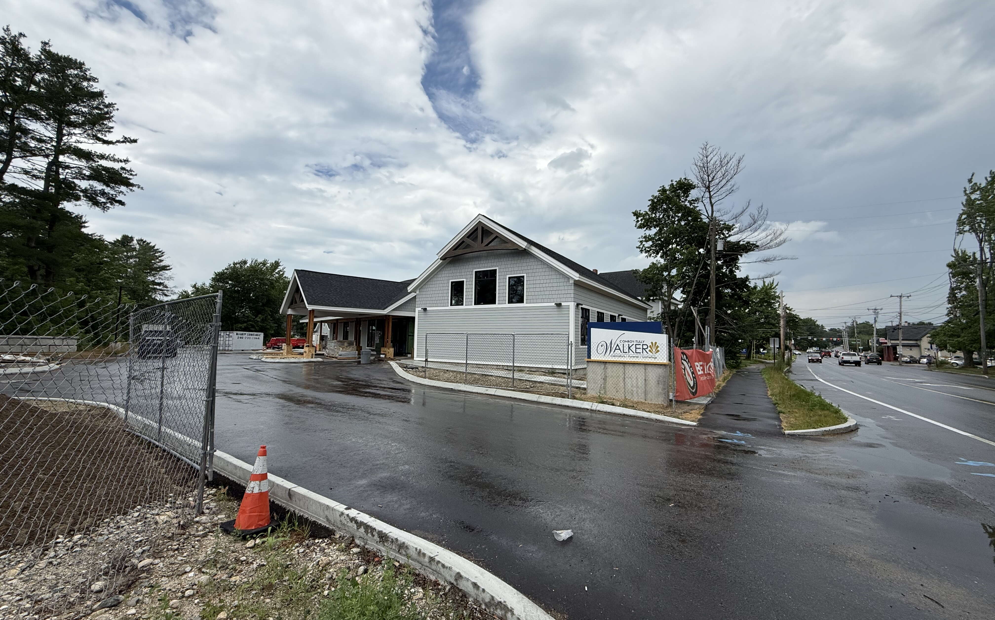 An exterior of a gray-sided building and a road and driveway.