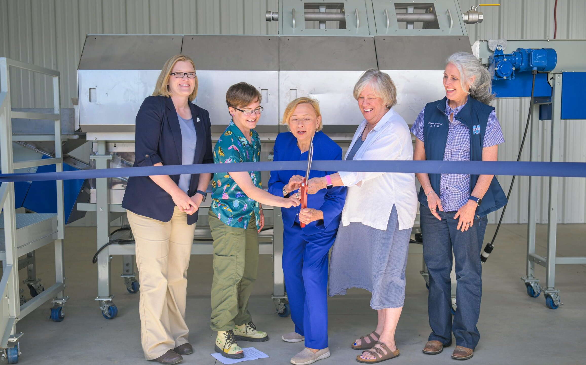 People pose with a ribbon and scissors.
