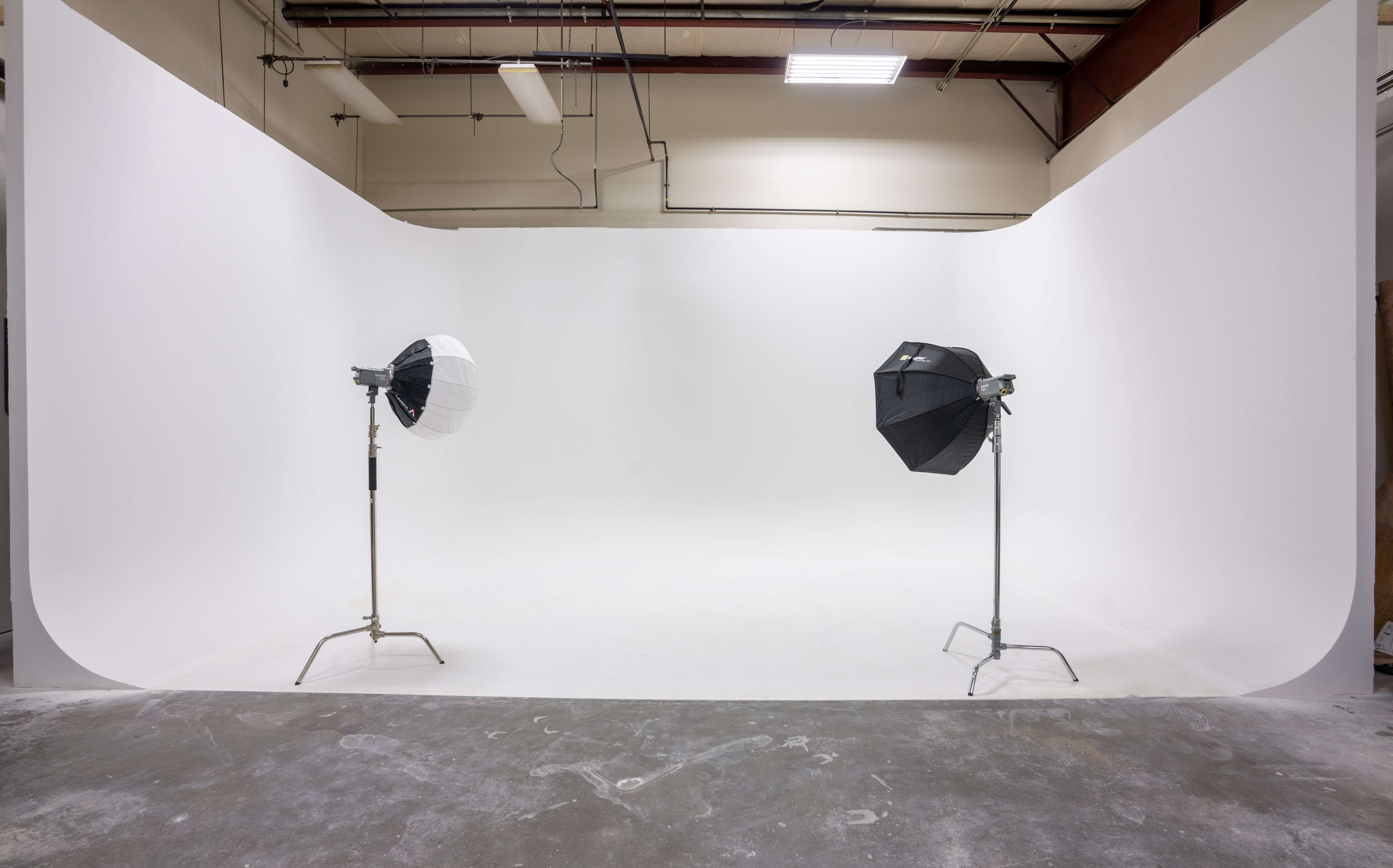 A room has a white backdrop and two lamps.