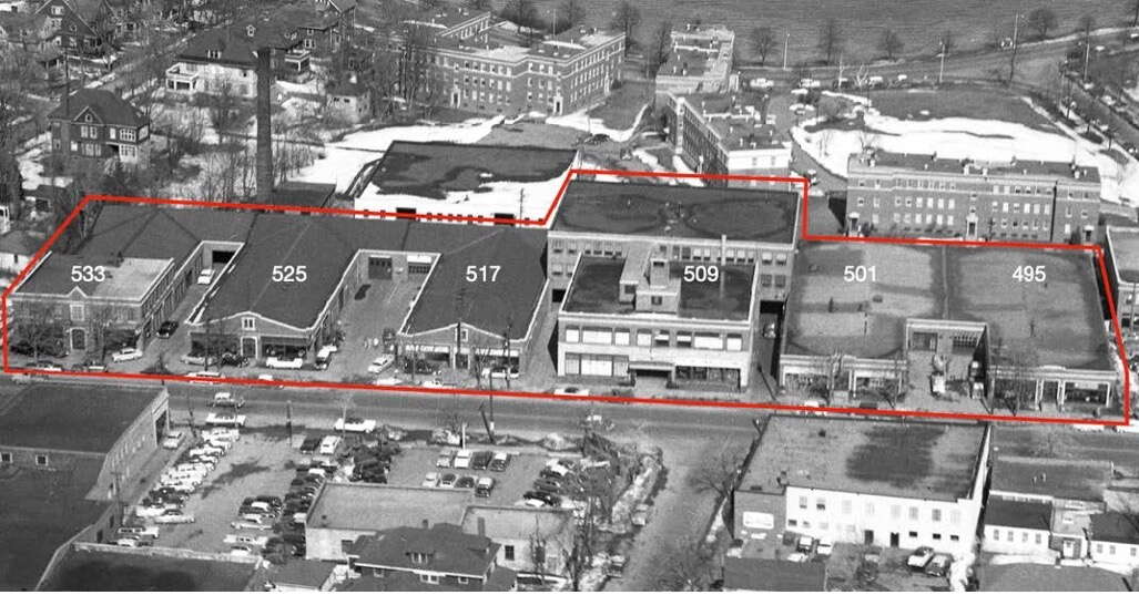 An aerial photo shows a row of buildings outlined in red.