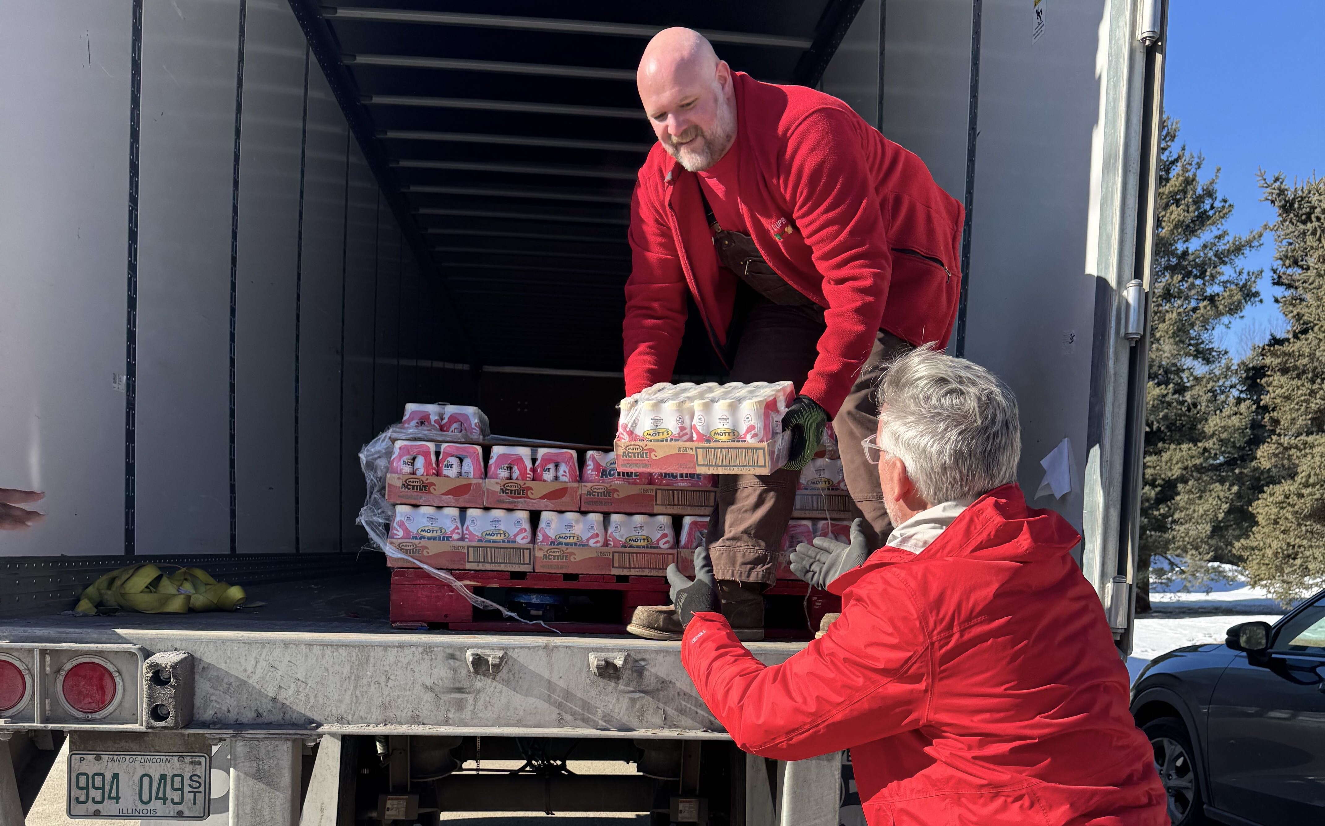 Two people unload goods from a truck.