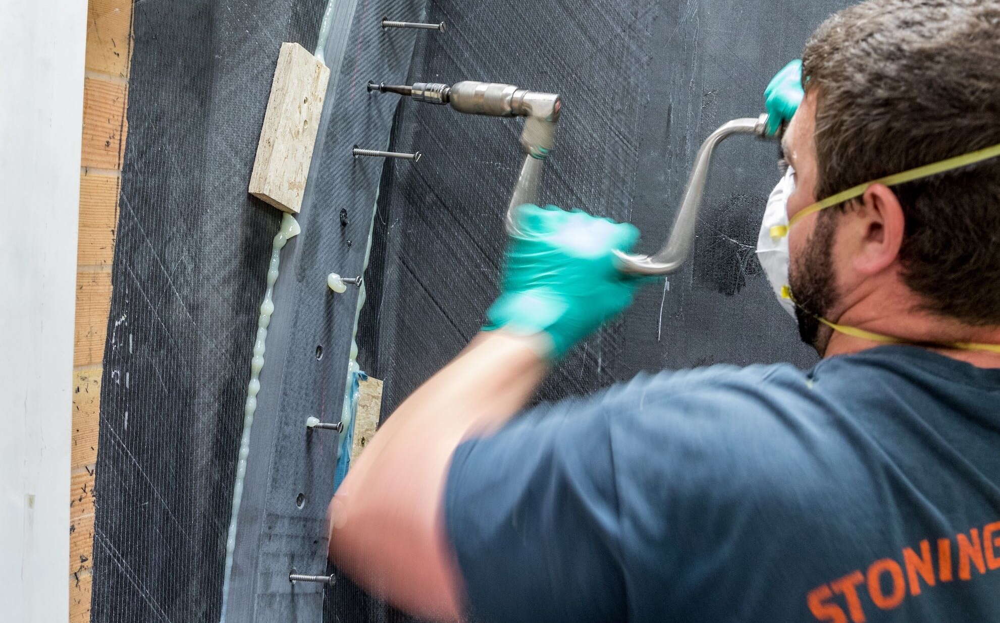 A person wears a mask and drills into something.