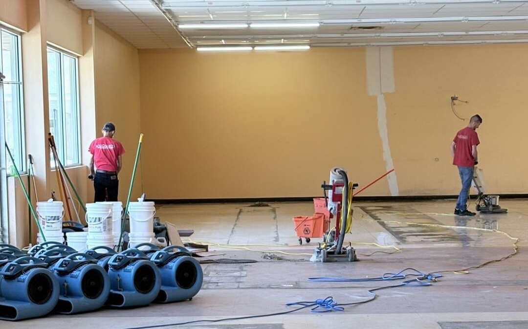 An interior view shows people buffing a floor.