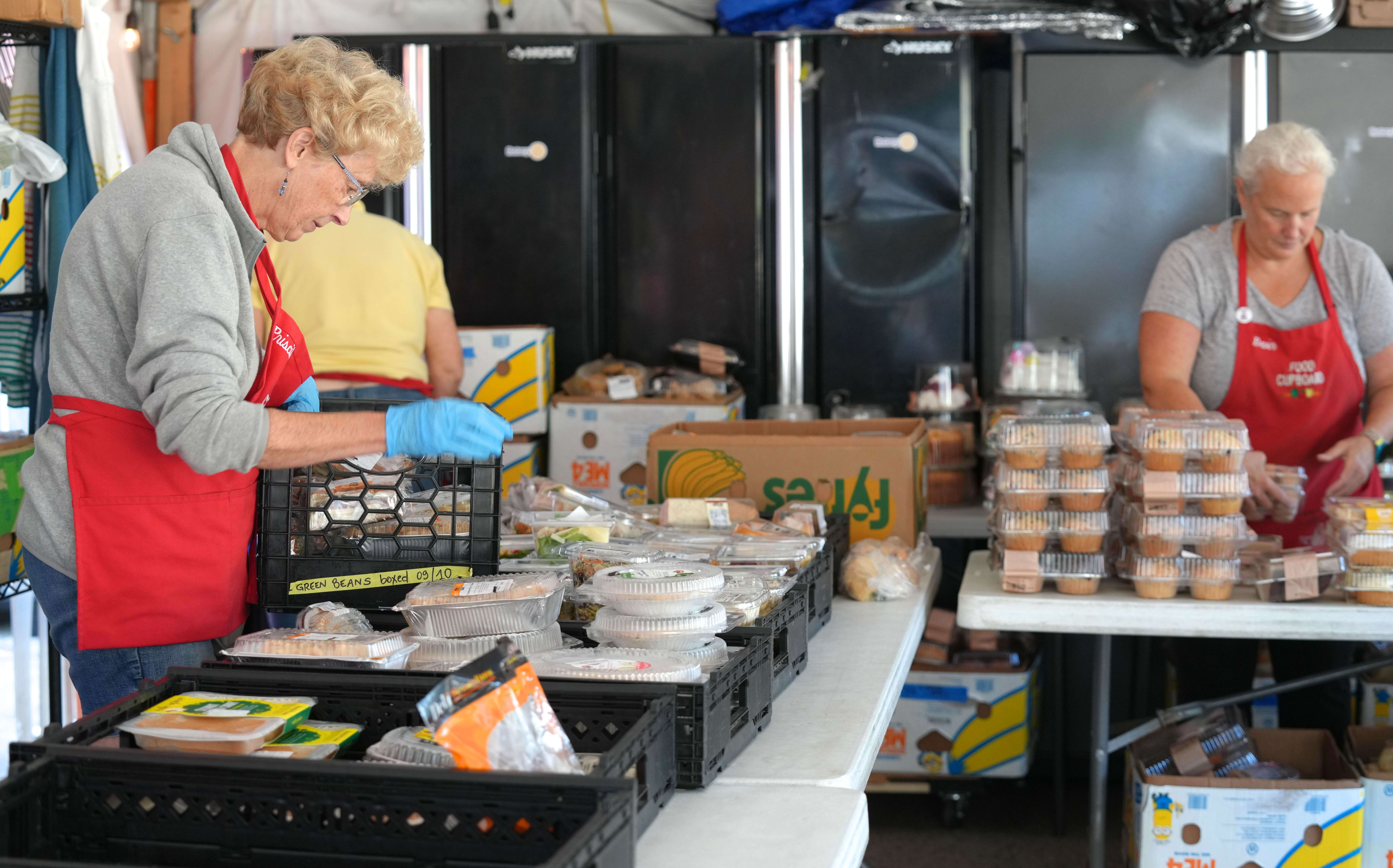 Two people unpack food at tables.