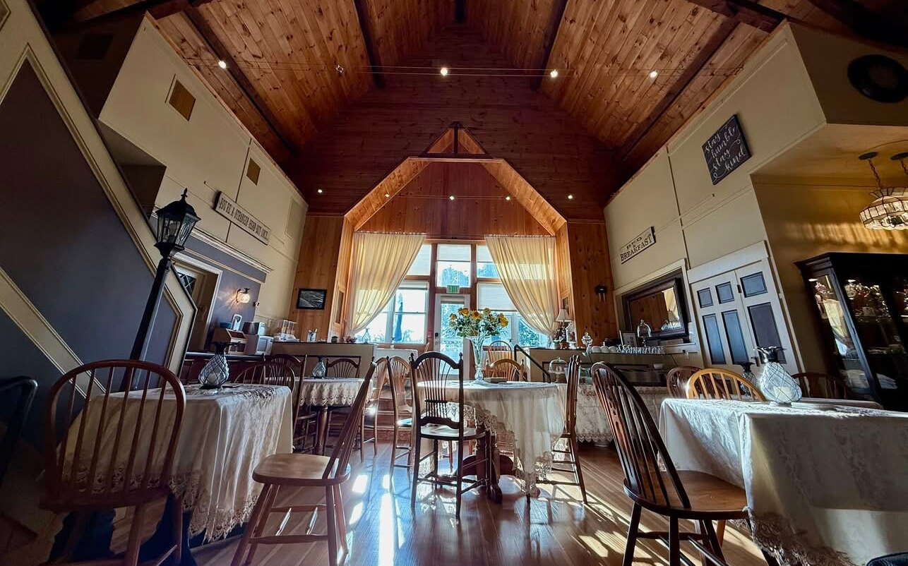 A room has a high ceiling and tables and chairs.