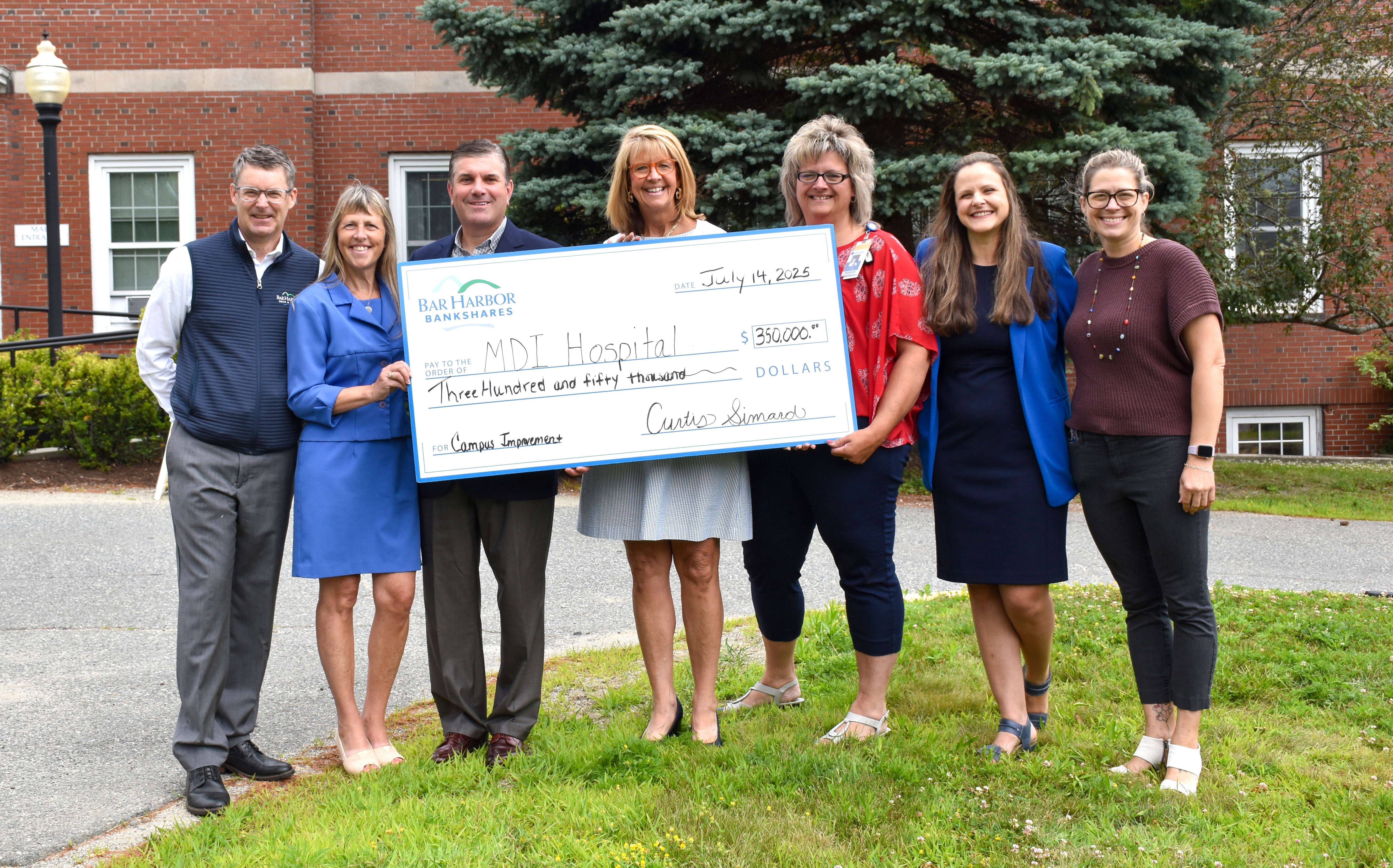 SEven people pose in a line with an oversize check.