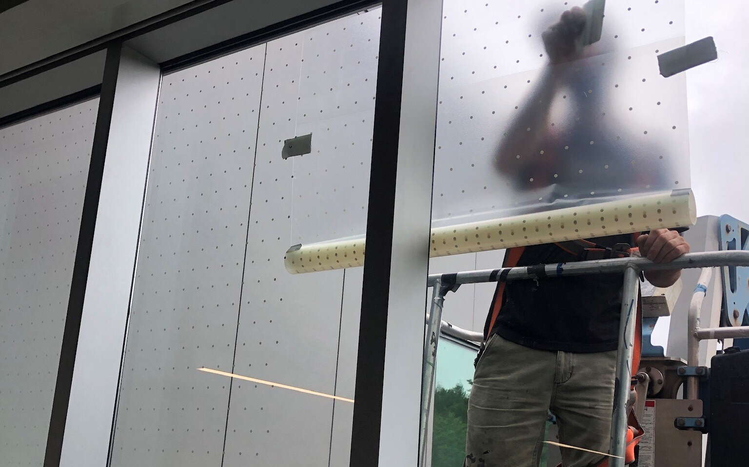 A person stands on scaffolding outside a window.