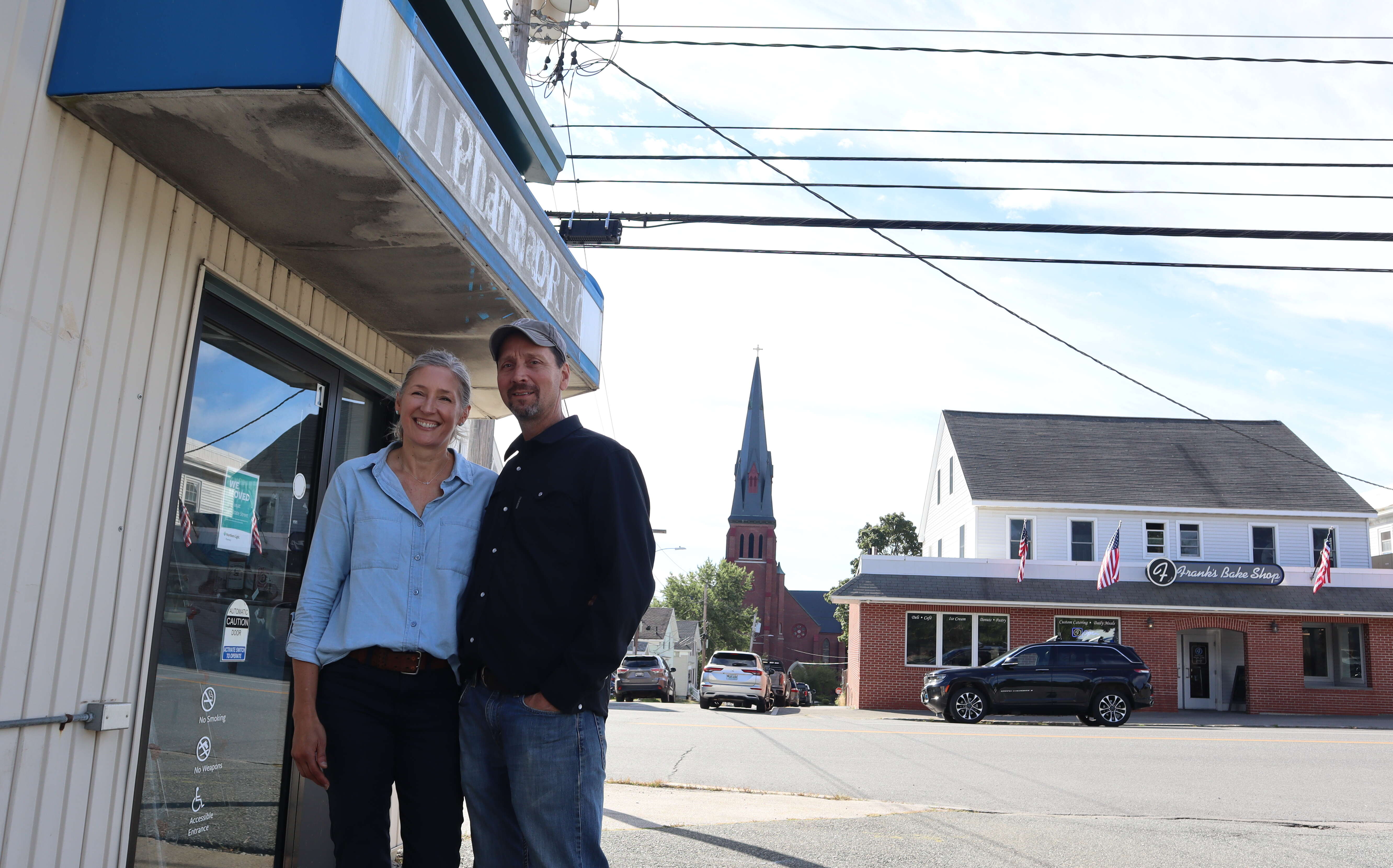 Two people stand outside of a building entry.
