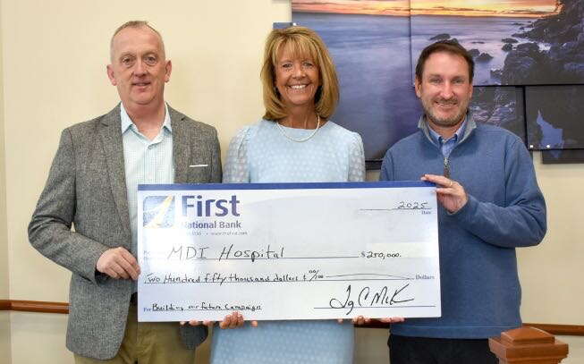 Three people pose in a line with an oversize check.