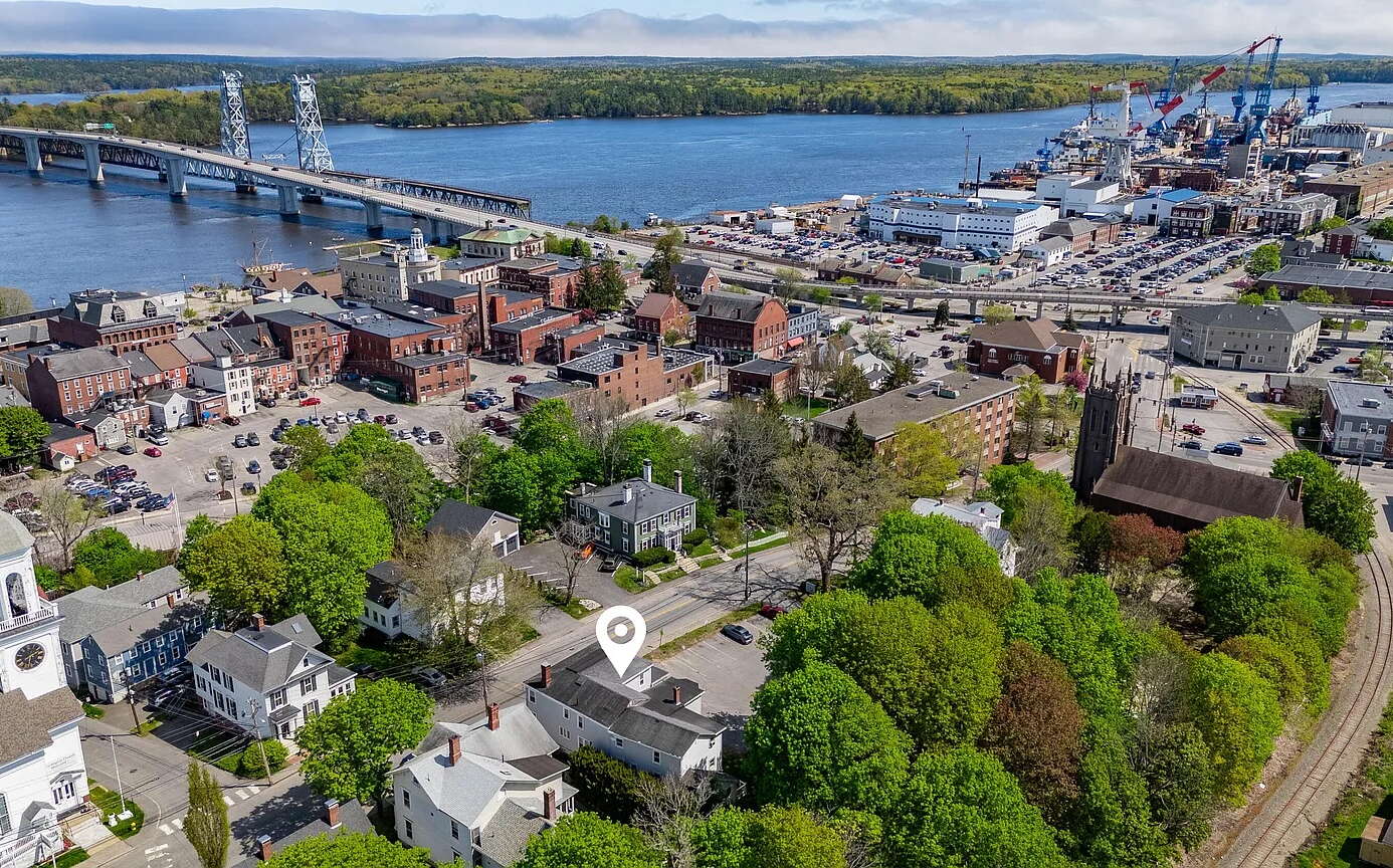 An aerial view shows numerous buildings and a river with a bridge.