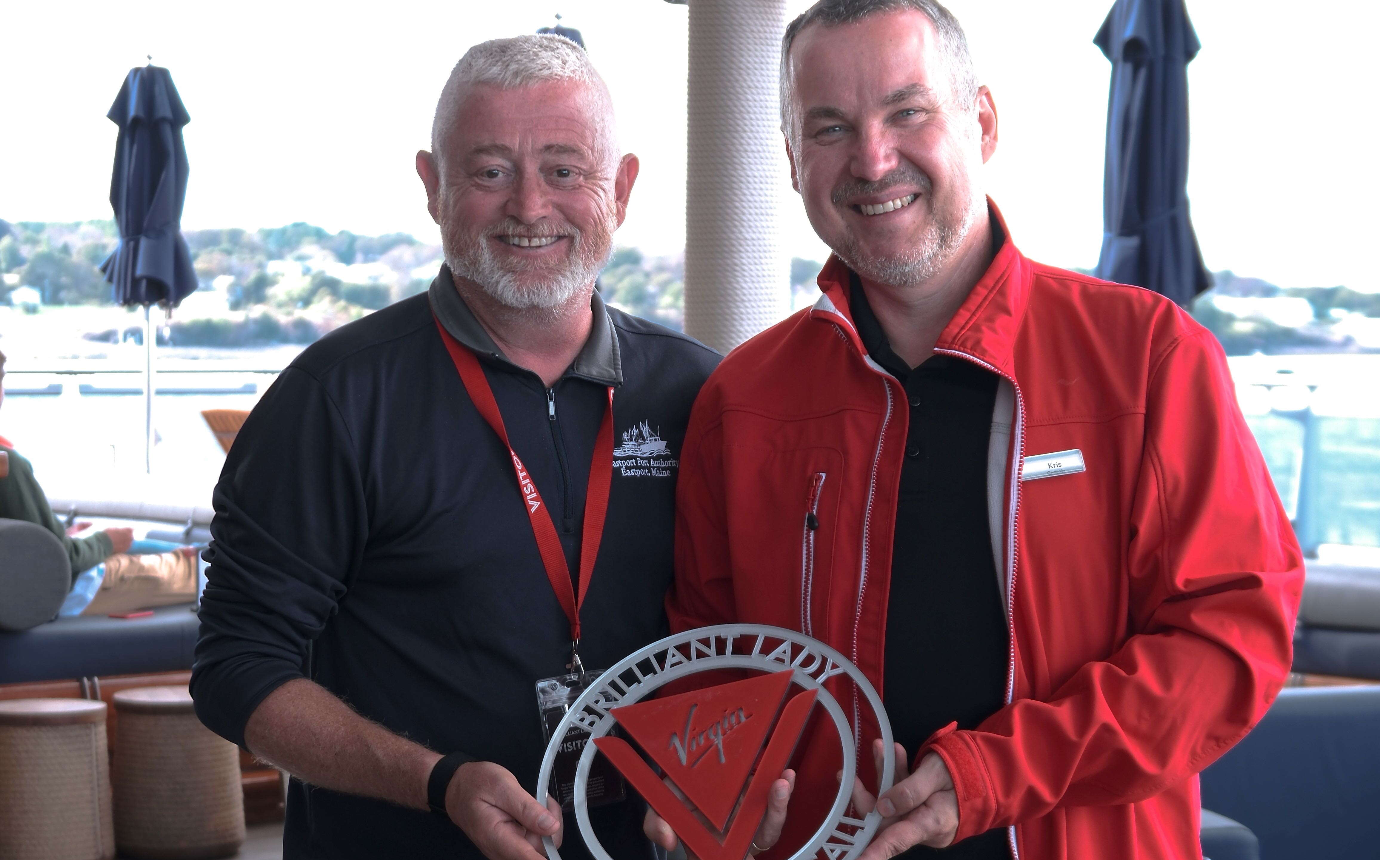 Two people pose with a plaque.