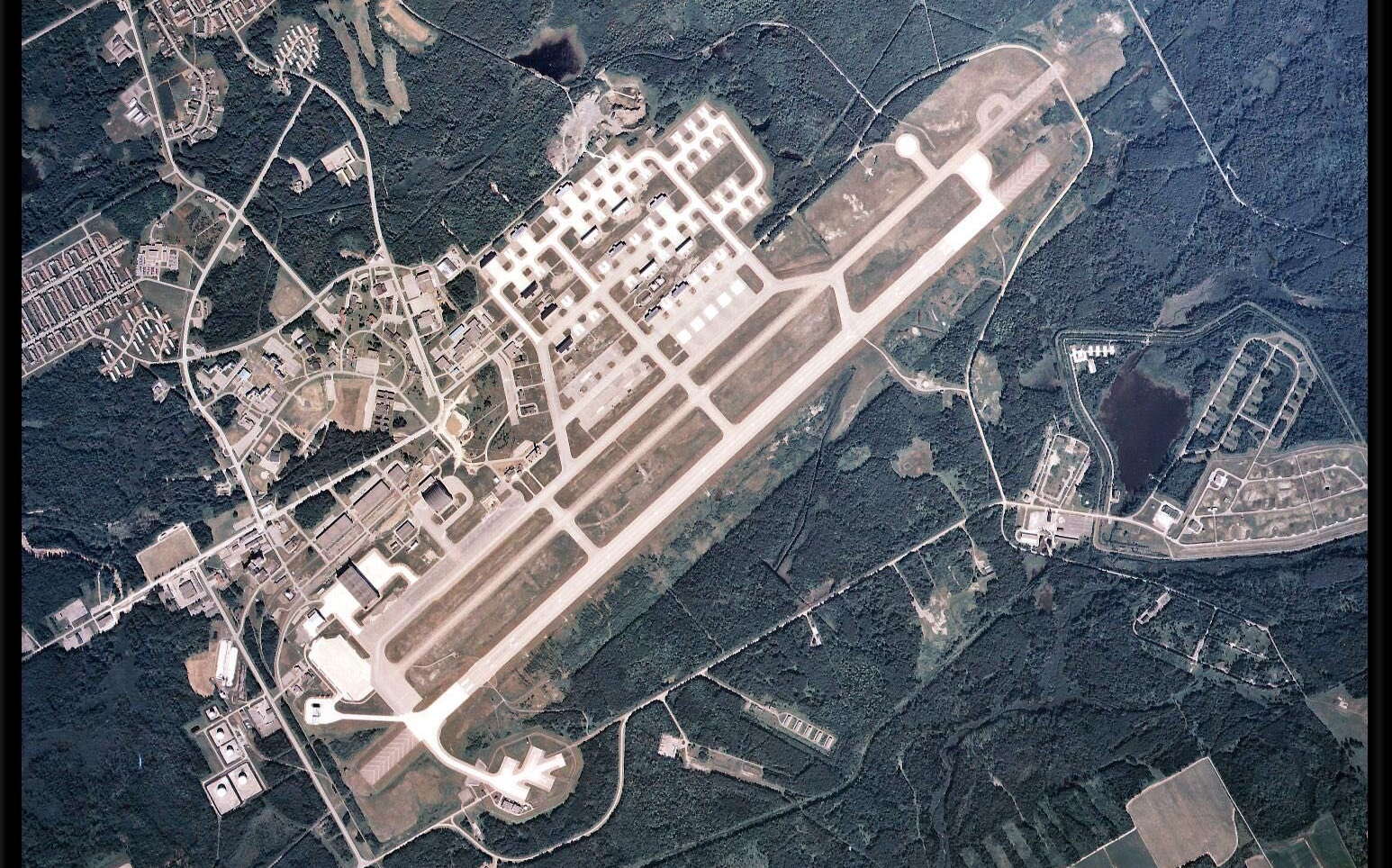 An aerial view shows an airstrip and buildings.