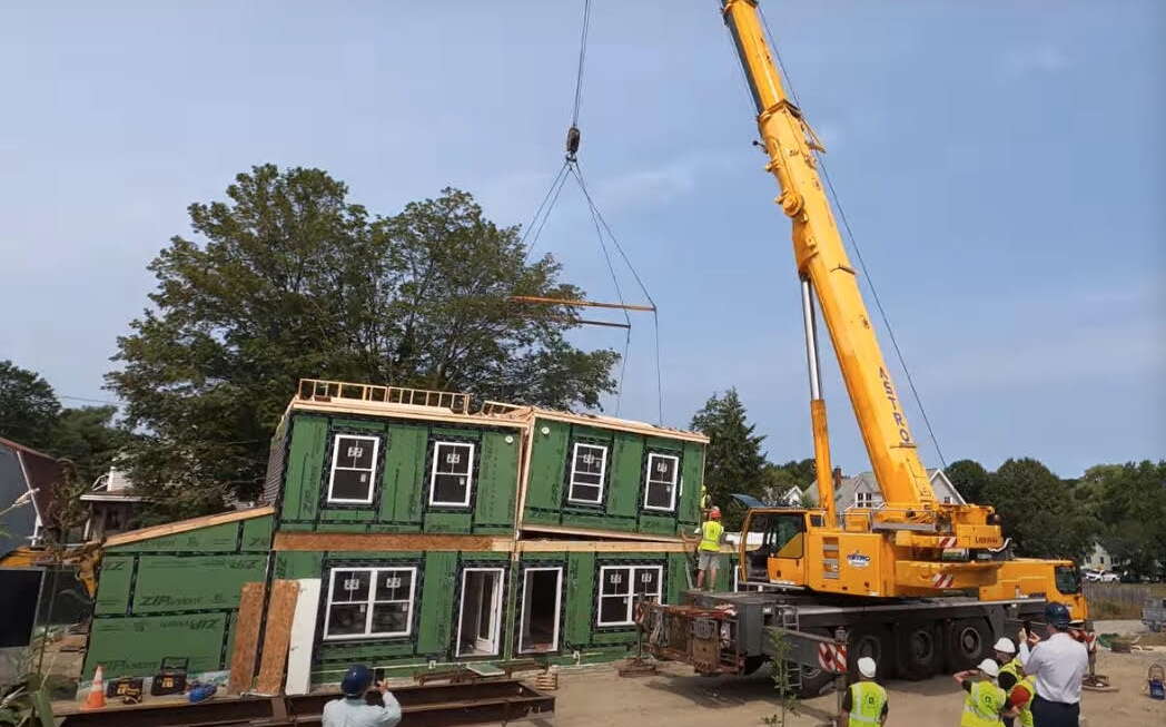a crane lowers a modular housing unit into place