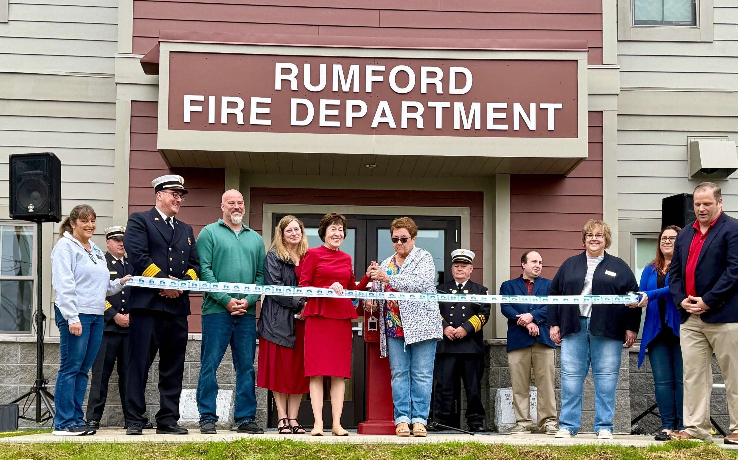 People stand in front of a buliding and cut a ribbon.