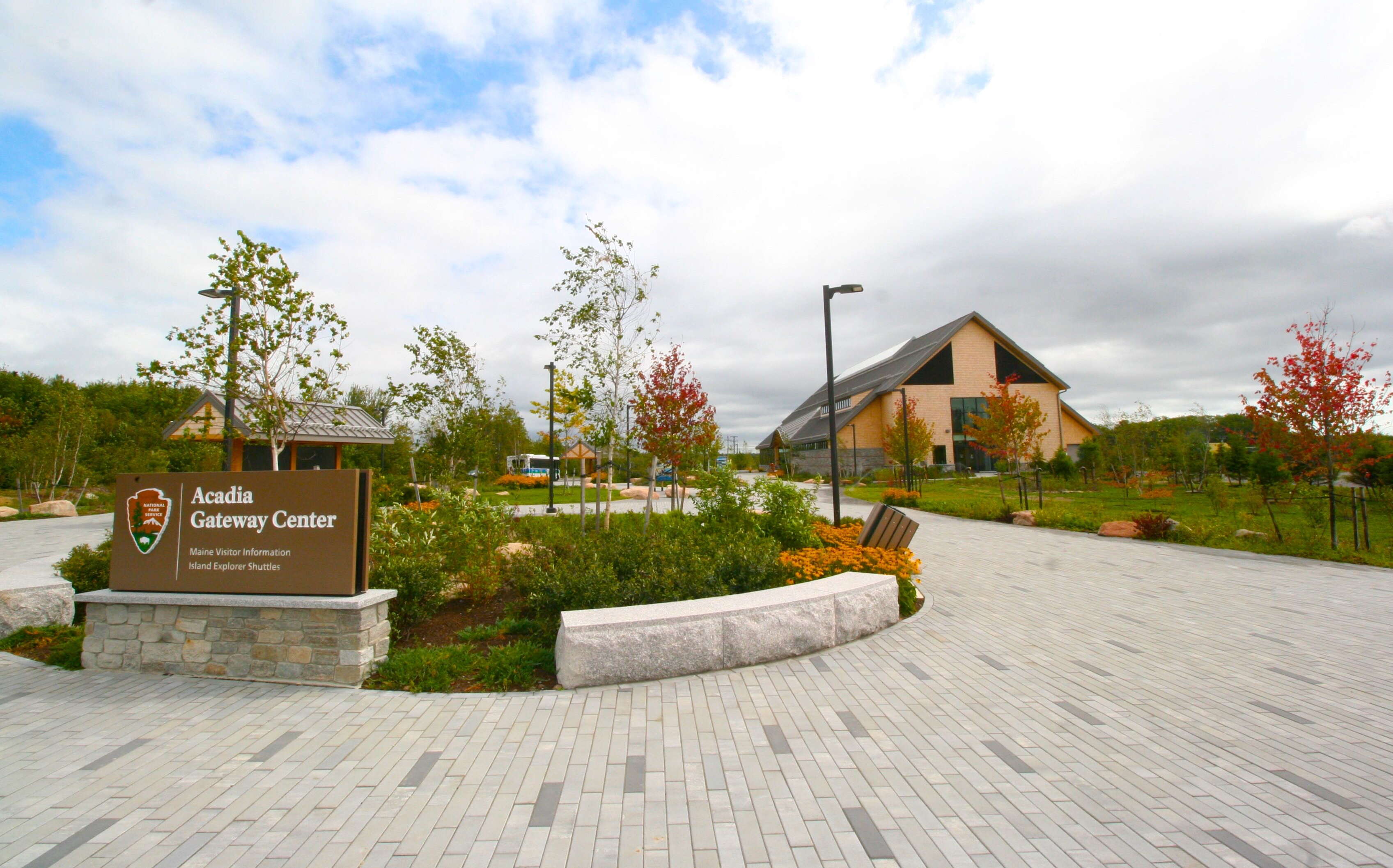 A plaza has flowers and a sign.