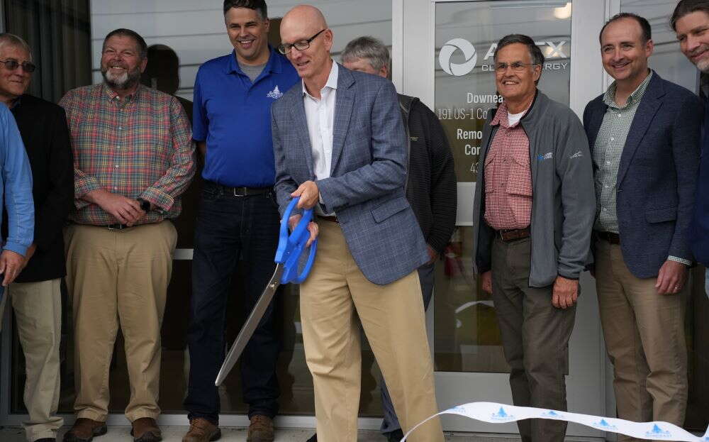 A person uses oversize scissors to cut a ribbon.