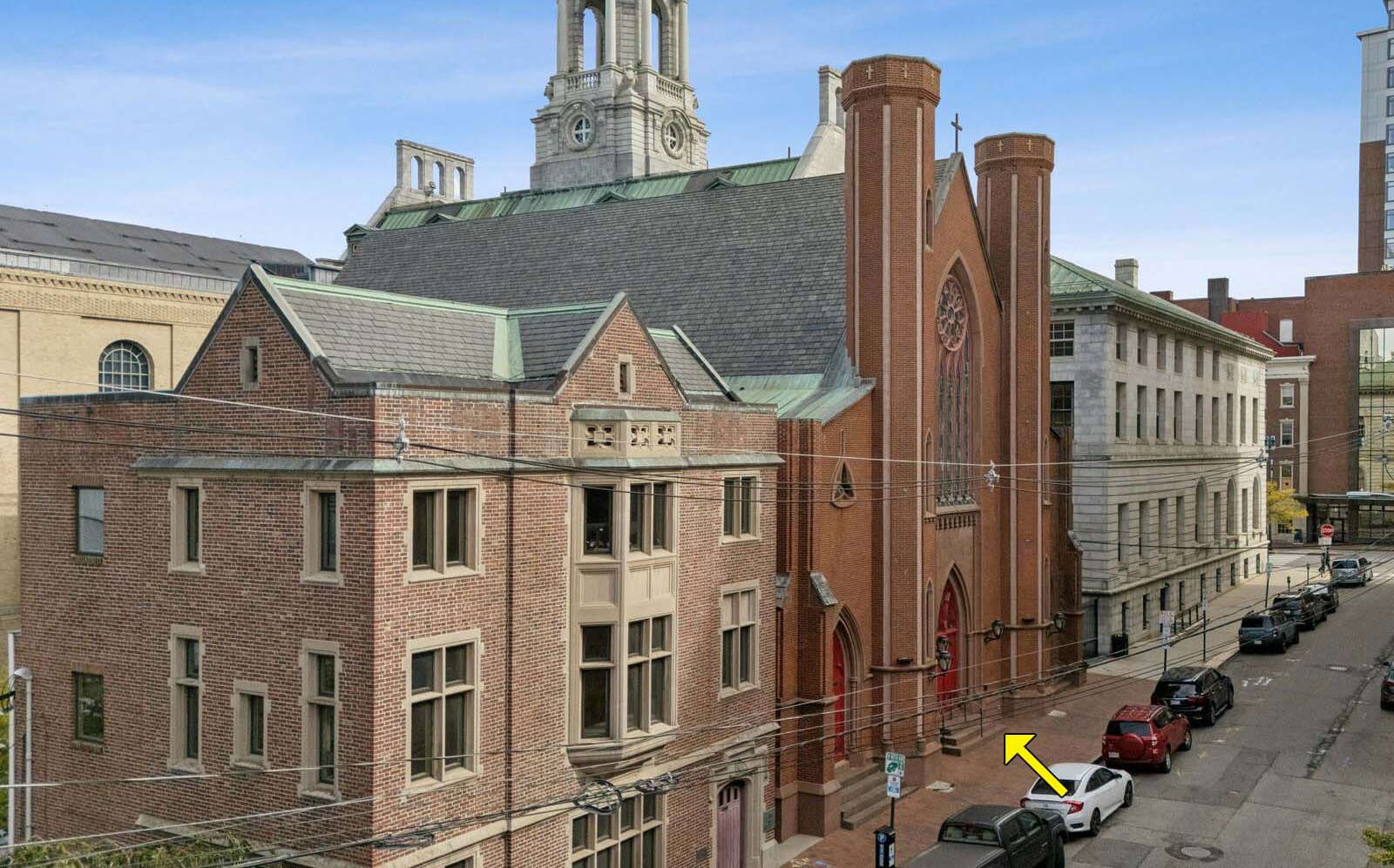 An old brick church and other bulldings line a street.