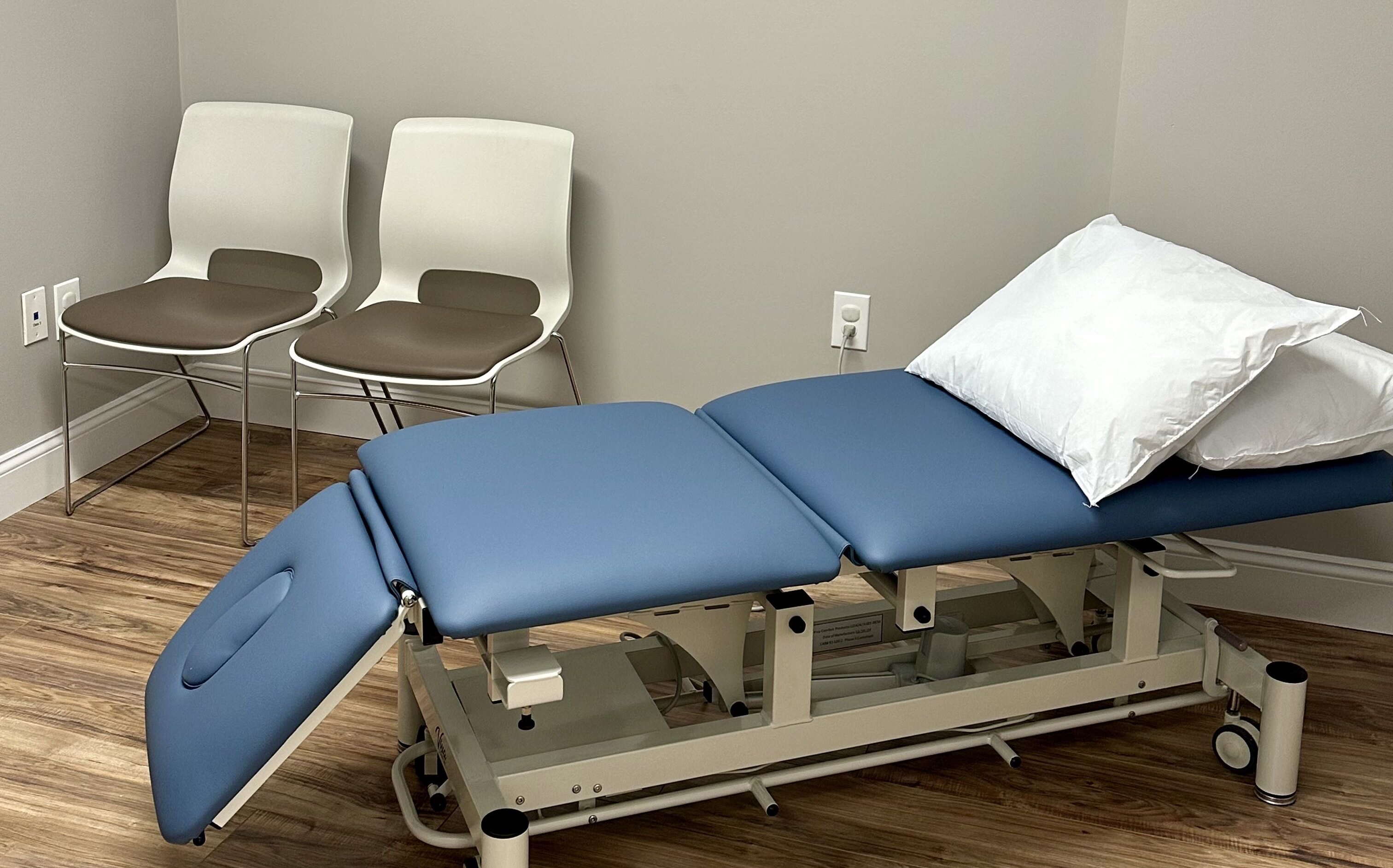 A room has a folding bed and two chairs.