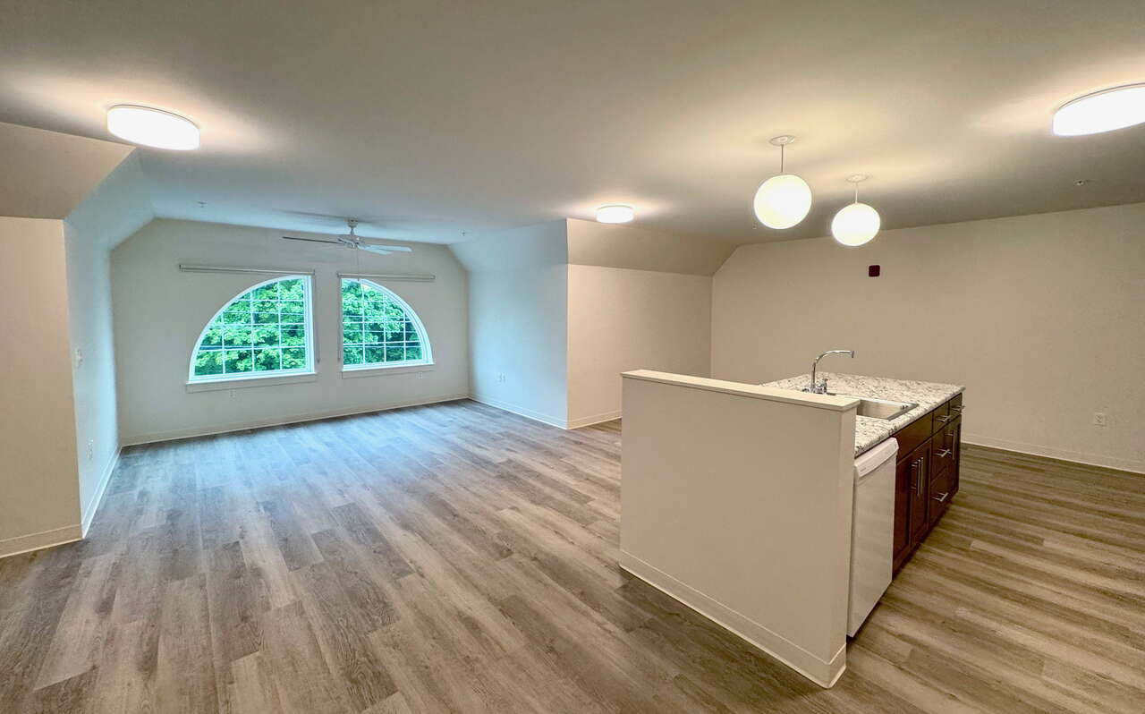 A room has windows and a kitchen counter with a sink.