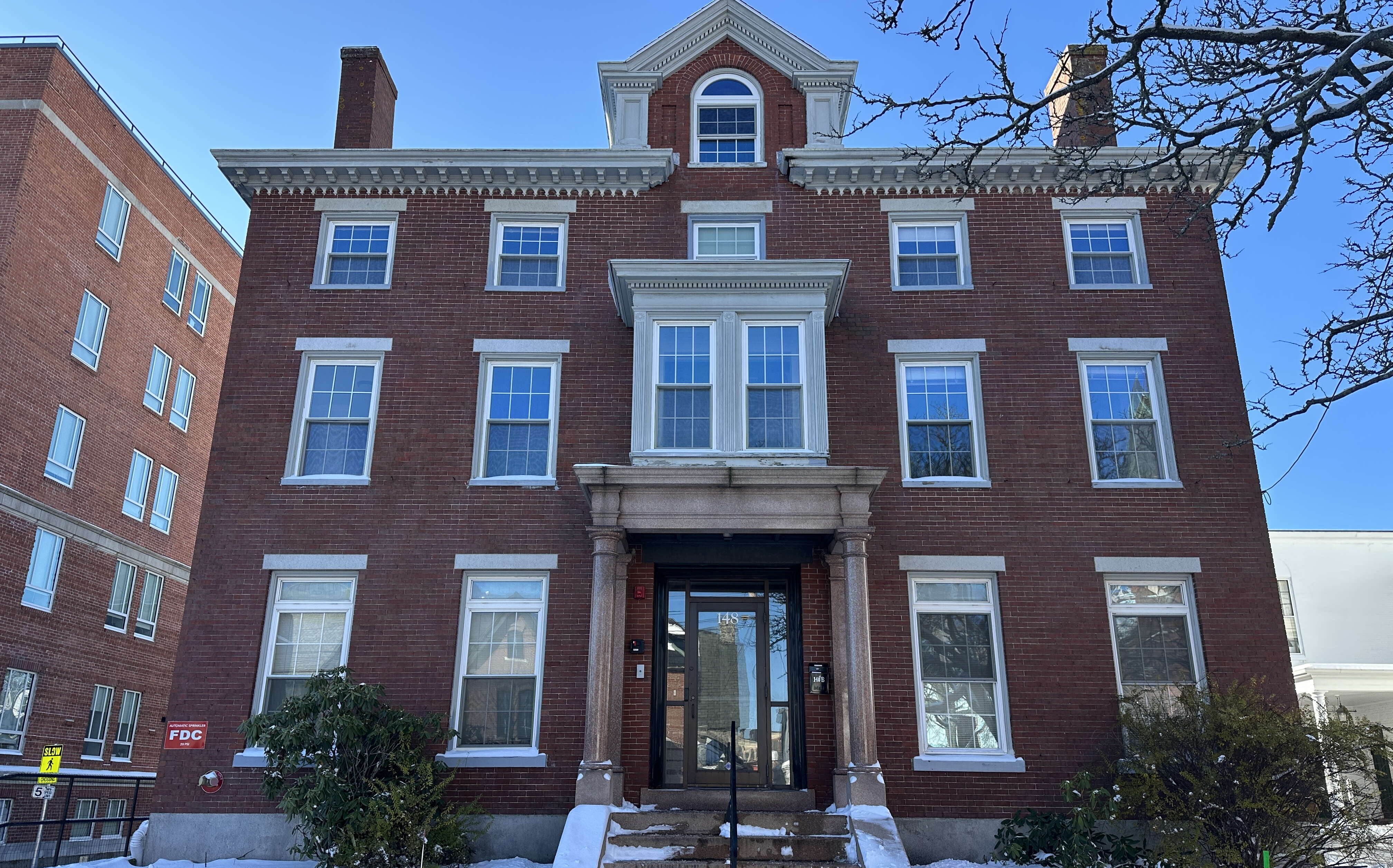 An exterior view of a brick building with s now around it.