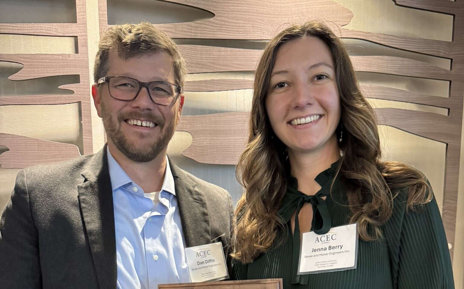 Two people pose with a plaque.