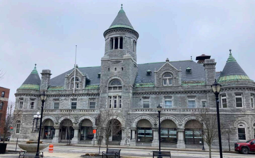 An exterior view of a gray stone building with arches.