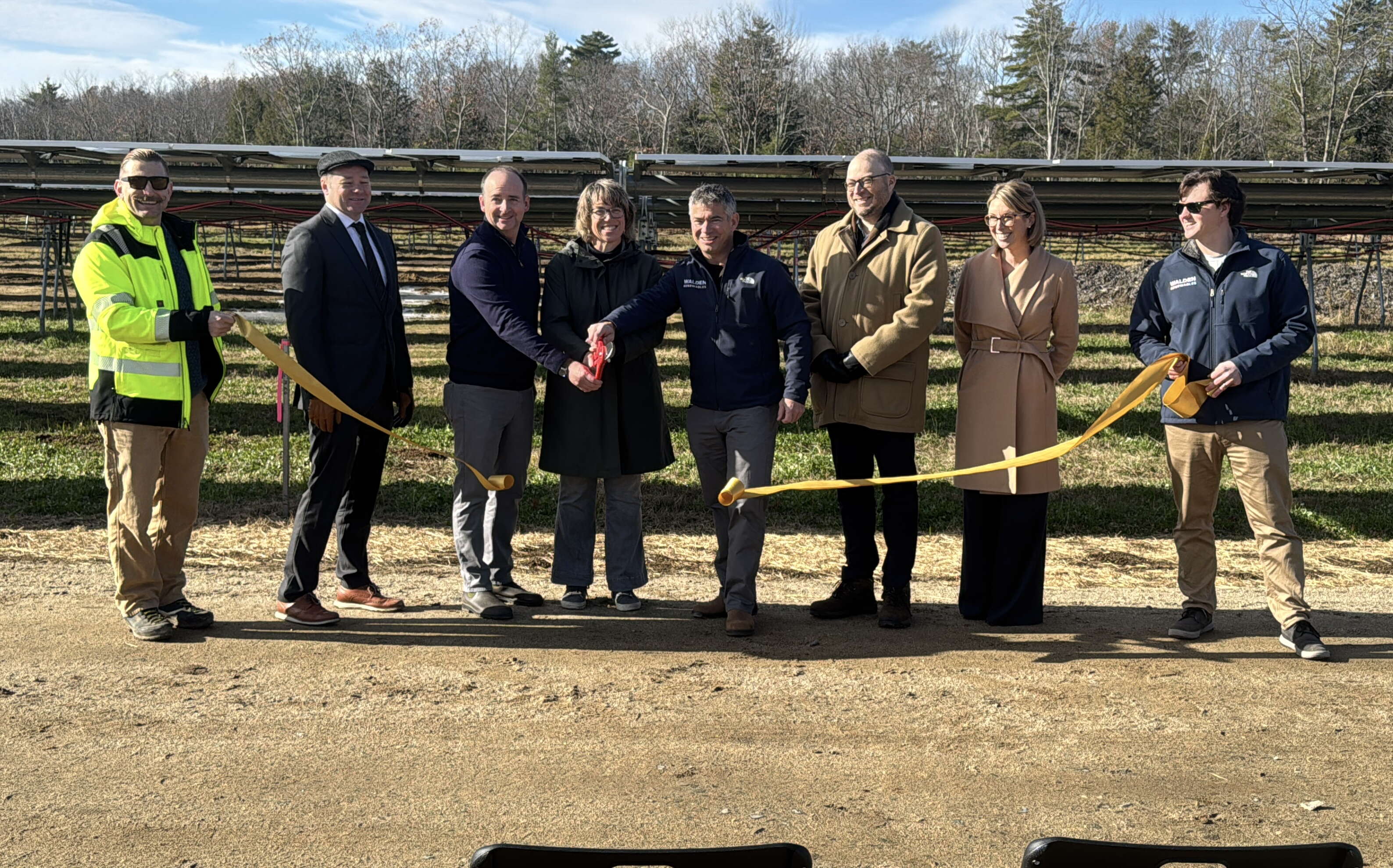 People  pose in a line with a ribbon.
