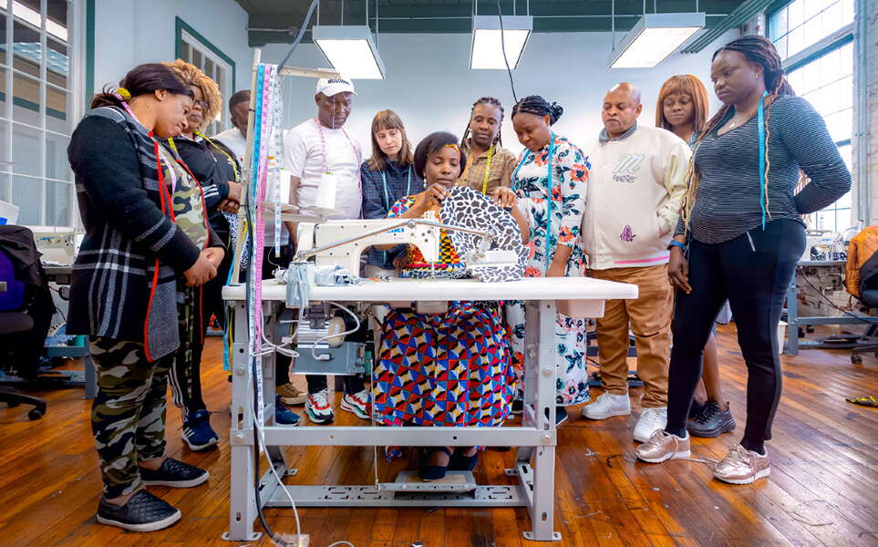 Immigrants around a sewing machine