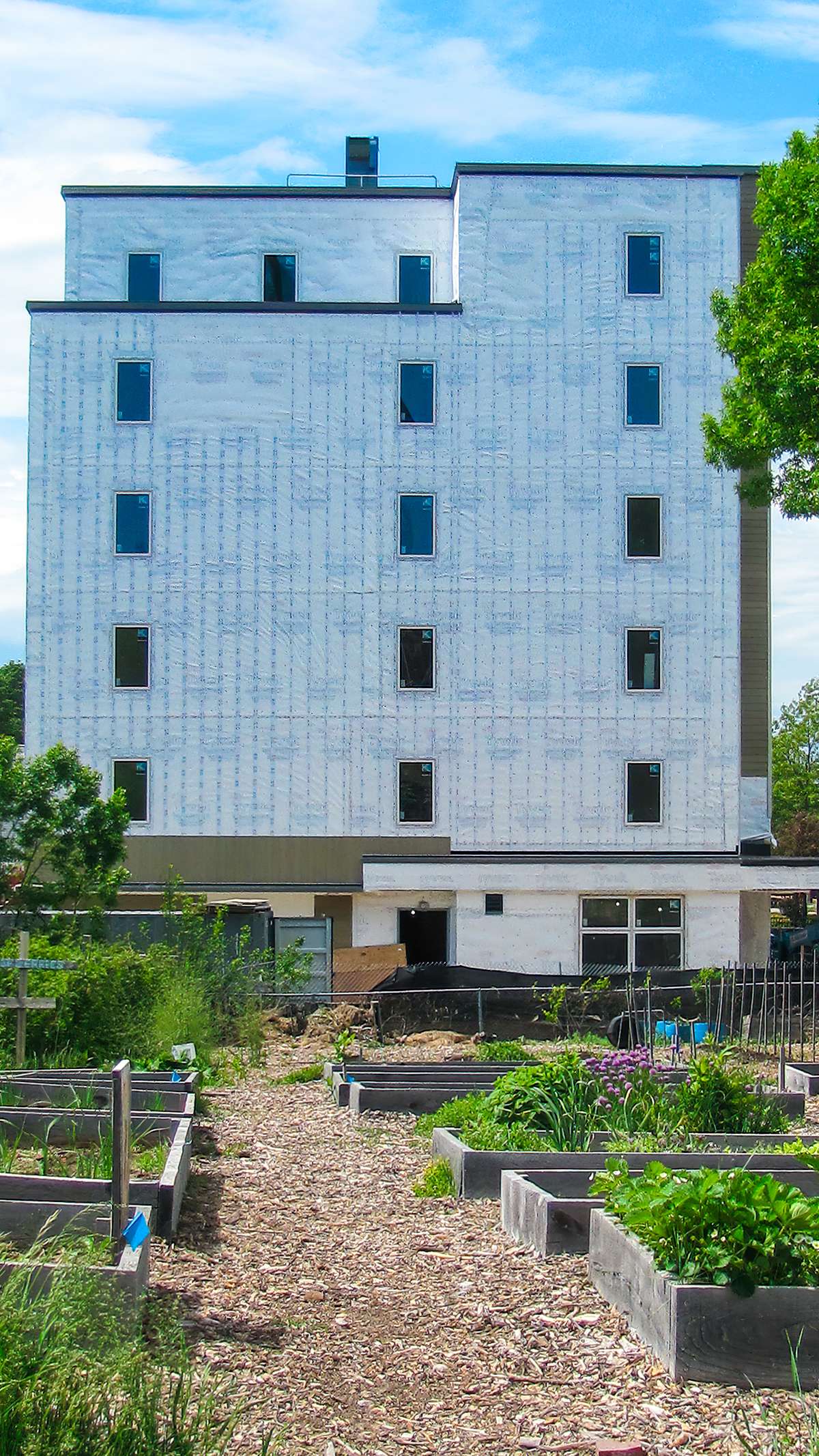 an under construction six story building with a garden in front