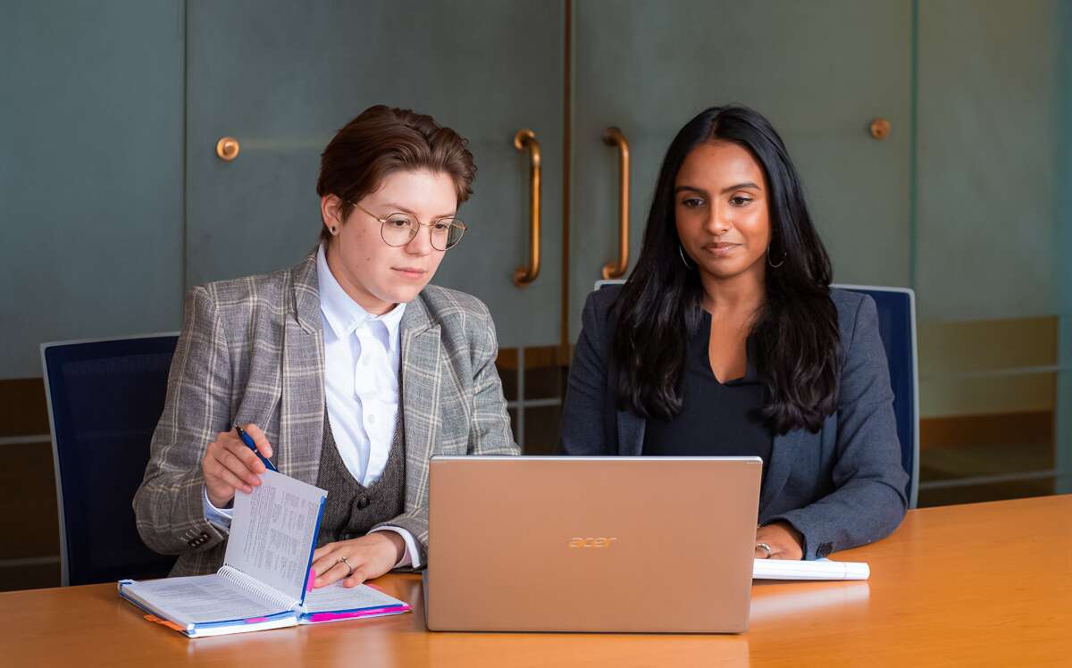 Two people seated working on a laptop.