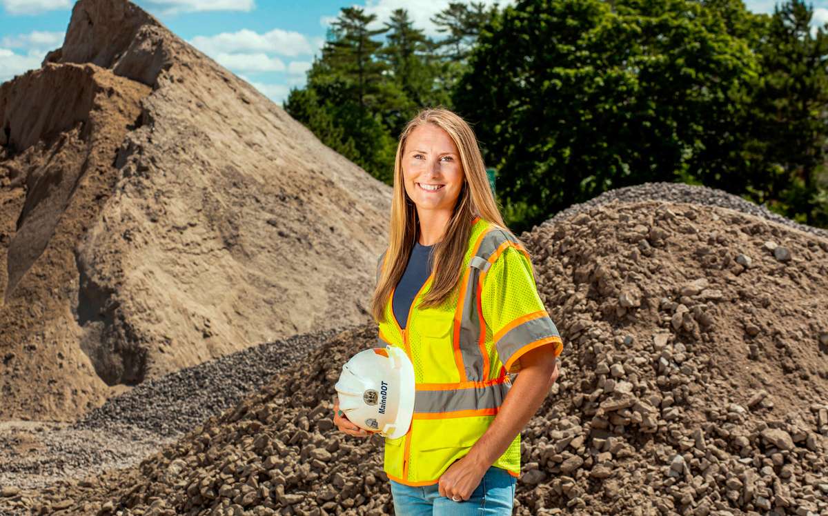 Kayla Stickney holding her hard hat and wearing safety vest