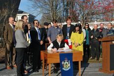 Gov. Mills signing executive order Nov. 27 surrounded by lawmakers.