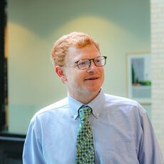 a man, white with red hair, in blue shirt and tie