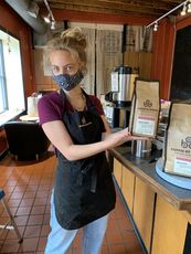 Barista wearing mask and holding Rebel Blend coffee packages