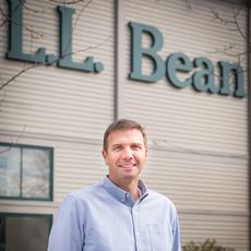 Photo of Steve Smith, president and CEO of L.L.Bean, in front of L.L. Bean building showing company logo 