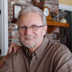 A smiling man with gray hair and a beard and glasses