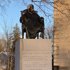 A statue of a man in judges robes on top of a granite pedestal that says Melville Weston Fuller and, among other things, chief justice of the U.S. Suprememe Court 1888-1910