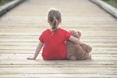photo of girl hugging bear (seen from behind)