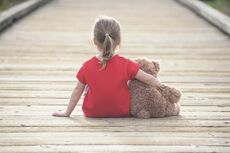 photo of girl hugging bear (seen from behind) 