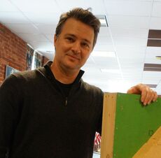 a man, white, holding a piece of board