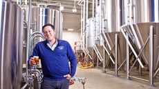 Kai Adams in the brewery holding a glass of beer 