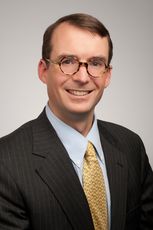 Chris Smith portrait in suit and tie, wearing glasses 